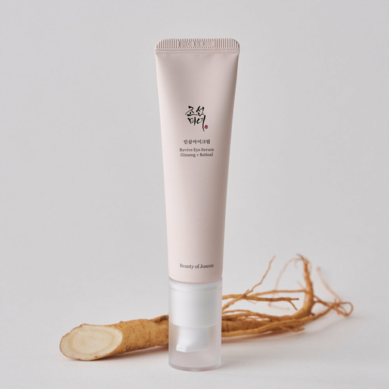 BEAUTY OF JOSEON Revive Eye Serum 30ml, tube rose sur fond clair avec racine de ginseng, contexte beauté.