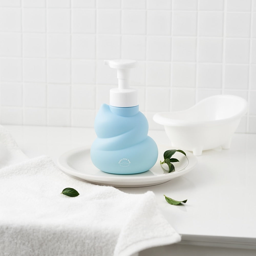 BELLBOY STUDIO Hippong Bubble Hand Wash : flacon bleu mousseux sur plateau près d’une salle de bain, serviettes et fleurs.