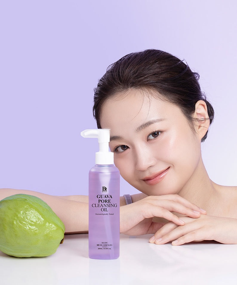 BENTON Guava Blackhead Pore Cleansing Oil 200ml posé à côté d'une personne souriante avec une goyave en arrière-plan.