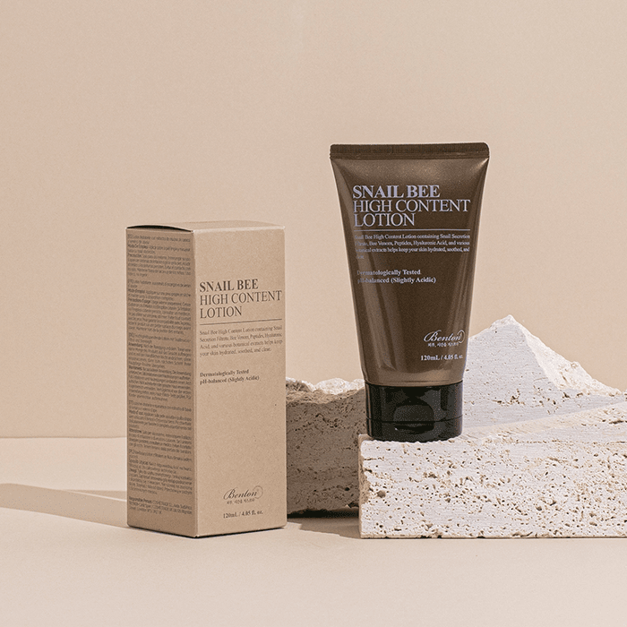 BENTON Snail Bee High Content Lotion 120ml par BENTON, tube et boîte sur décor beige, contexte cosmétique.