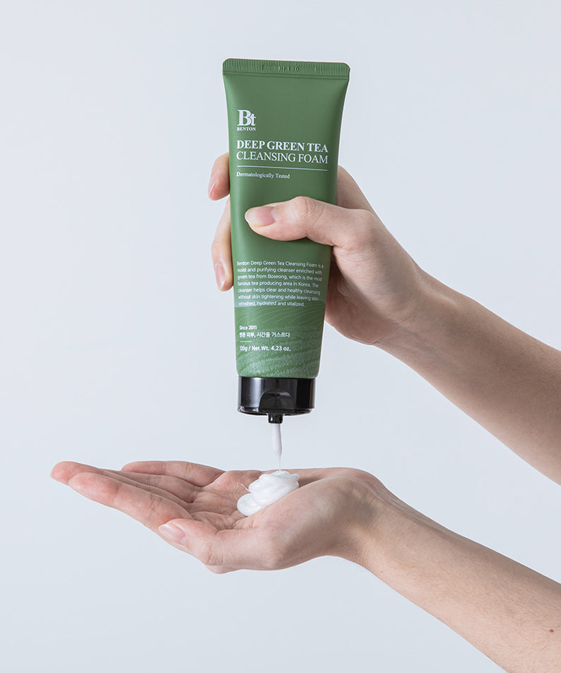 Décris l'image en français : BENTON Deep Green Tea Cleansing Foam 120g, tube vert de la marque BENTON, mousse sur la main.