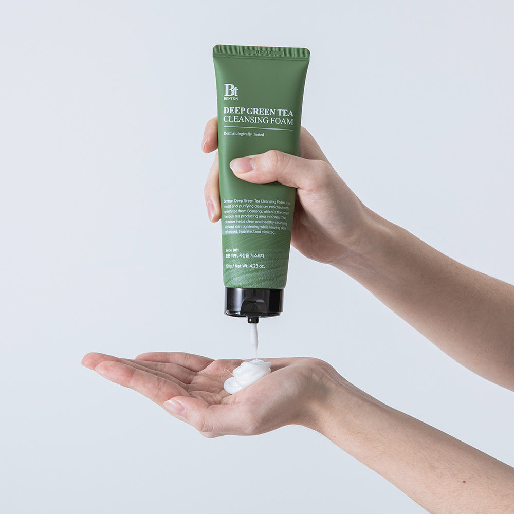 Décris l'image en français : BENTON Deep Green Tea Cleansing Foam 120g, tube vert de la marque BENTON, mousse sur la main.