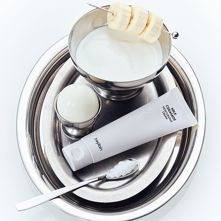 BEPLAIN Milk Ceramide Moisturizing Cream 50ml, tube sur plateau avec lotion crème et banane, contexte cosmétique blanc