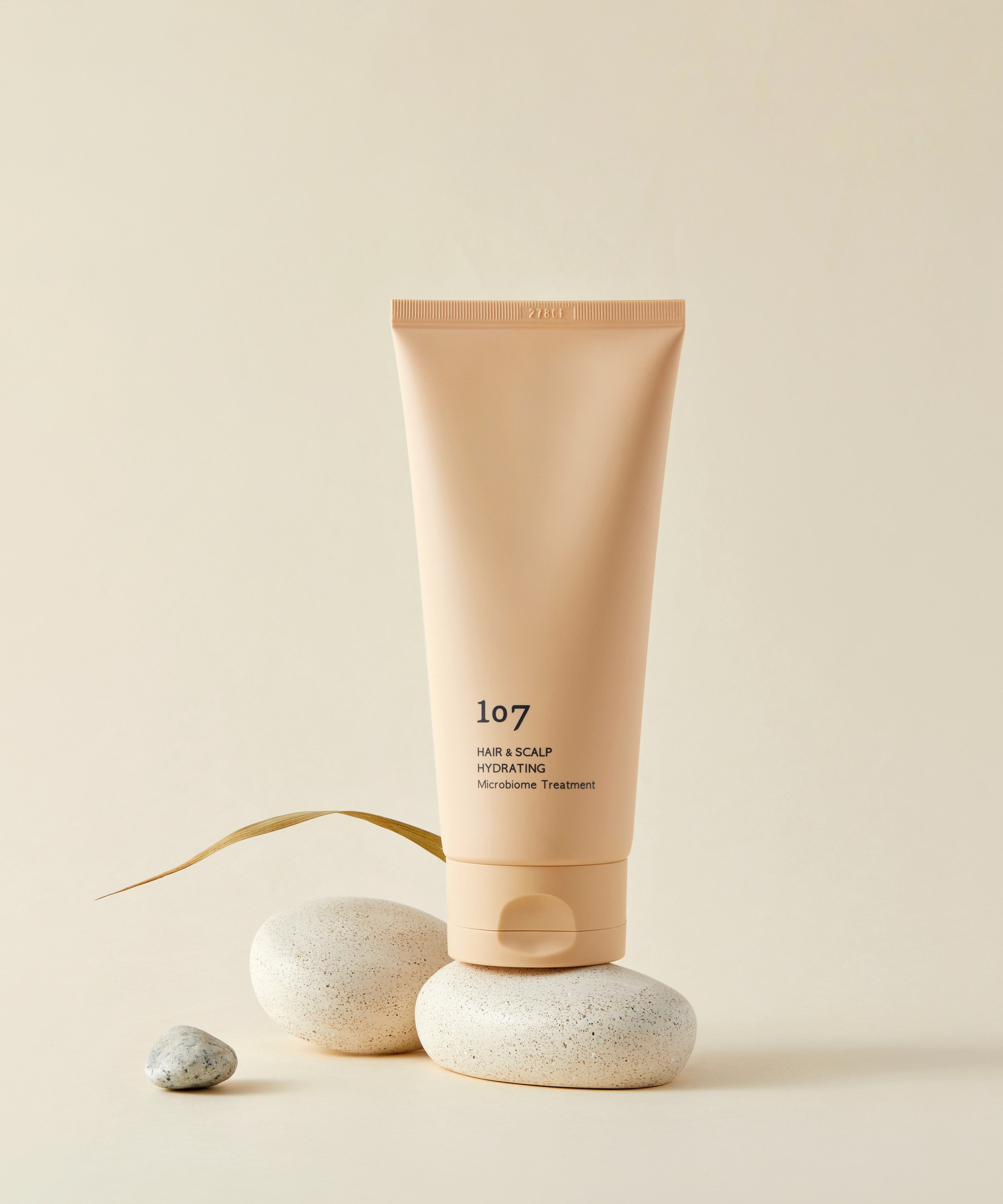 107 Hair & Scalp Hydrating Microbiome Treatment 180ml de la marque 107, tube crème sur pierres, fond beige.
