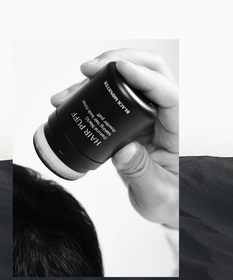 BLACK MONSTER Hair Black Puff Natural Black, main tenant le produit sur fond clair, marque BLACK MONSTER en contexte visuel