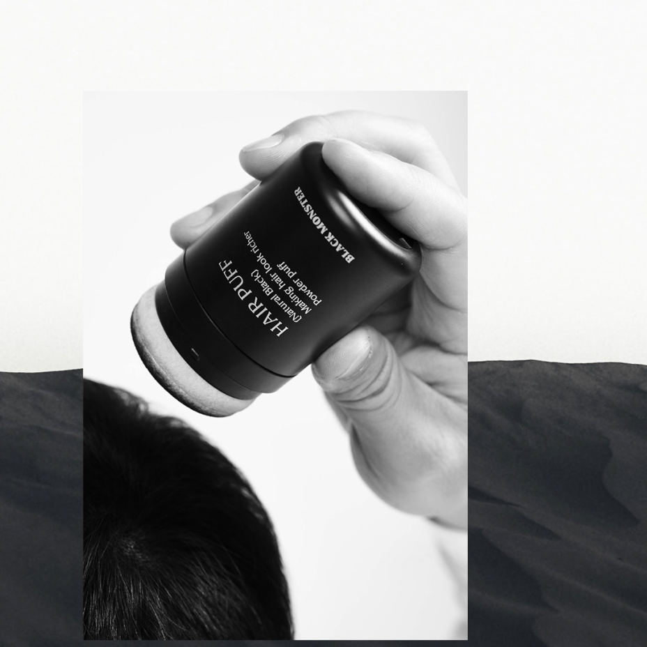 BLACK MONSTER Hair Black Puff Natural Black, main tenant le produit sur fond clair, marque BLACK MONSTER en contexte visuel