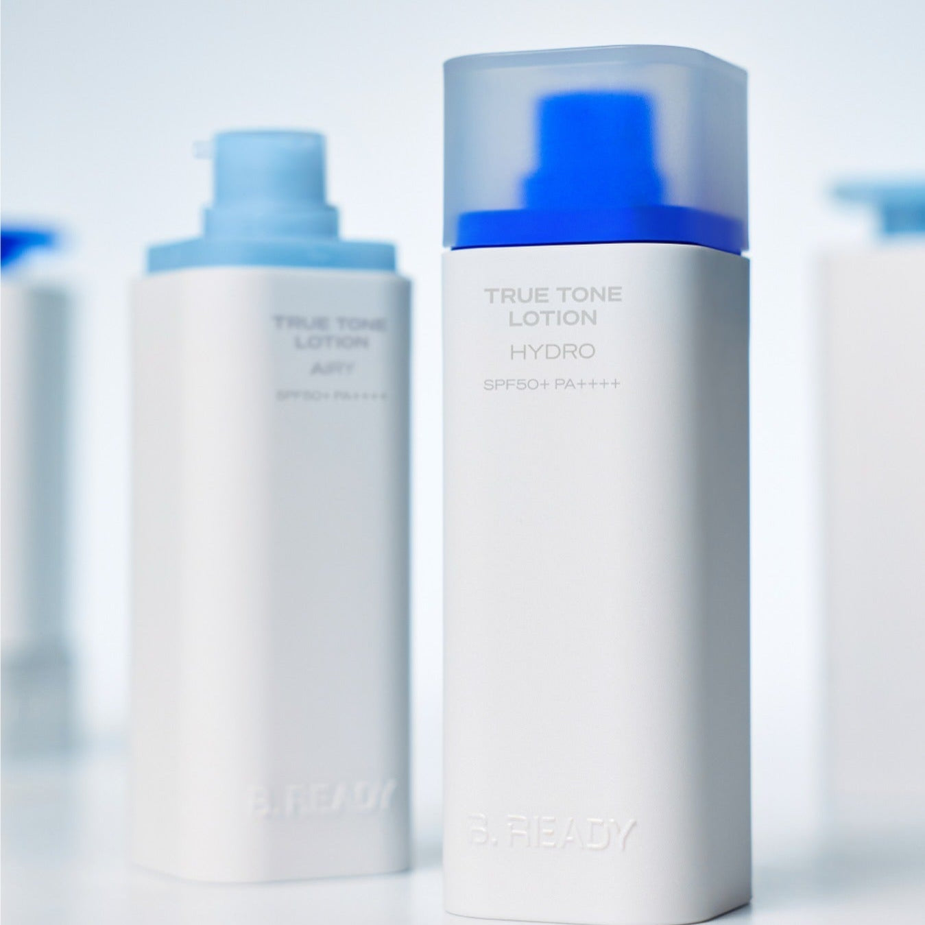 B.READY True Tone Lotion 2.0 40ml, flacons cosmétiques en arrière-plan blanc et bleu, marque B.READY, contexte studio.