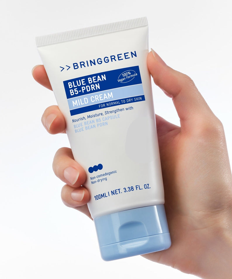 Main tenant BRINGGREEN Blue Bean B5-PDRN Mild Cream 100ml, tube crème bleu, marque visible sur fond clair.