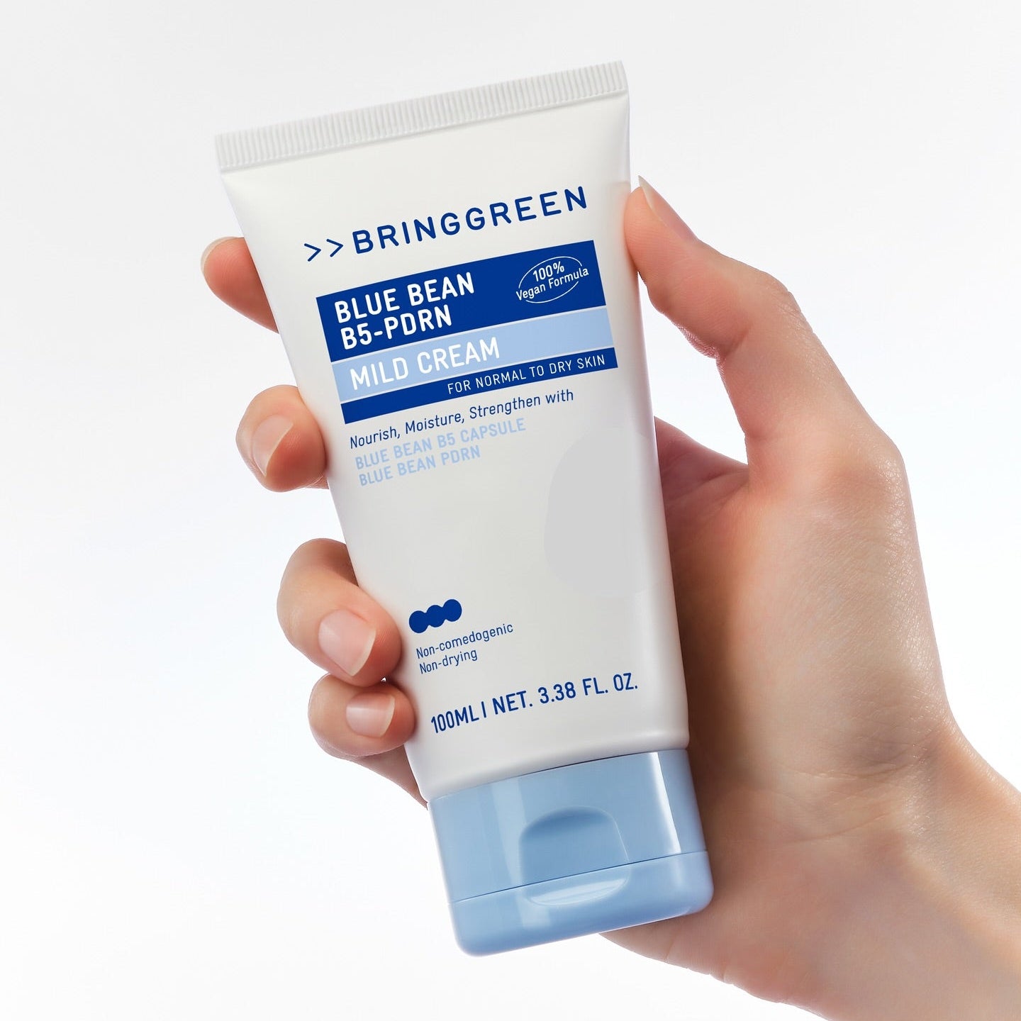 Main tenant BRINGGREEN Blue Bean B5-PDRN Mild Cream 100ml, tube crème bleu, marque visible sur fond clair.