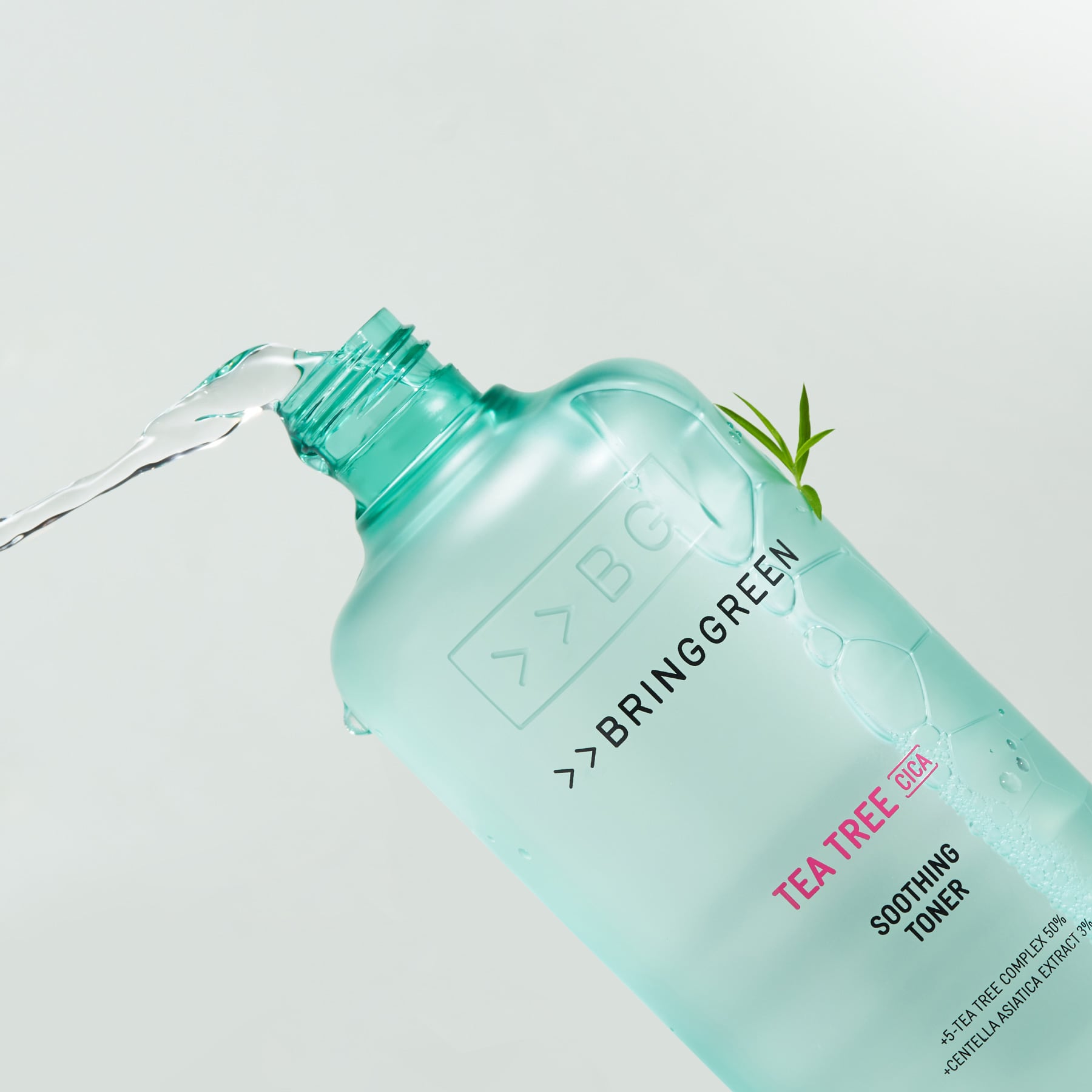 BRINGGREEN Teatree Cica Soothing Toner 250ml/500ml, flacon vert versé sur fond clair, ambiance soin visage