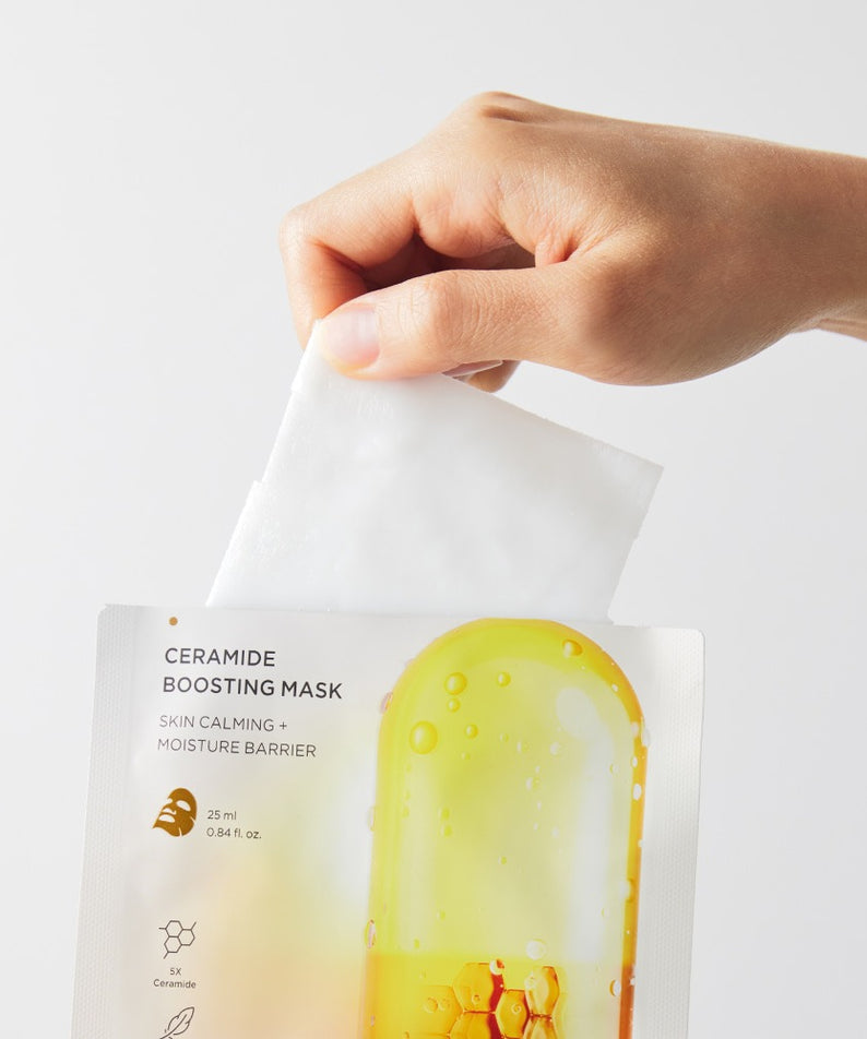 Décris l’image en français : BRTC Ceramide Boosting Mask 10 Sheets de BRTC, main tient un masque en sachet.