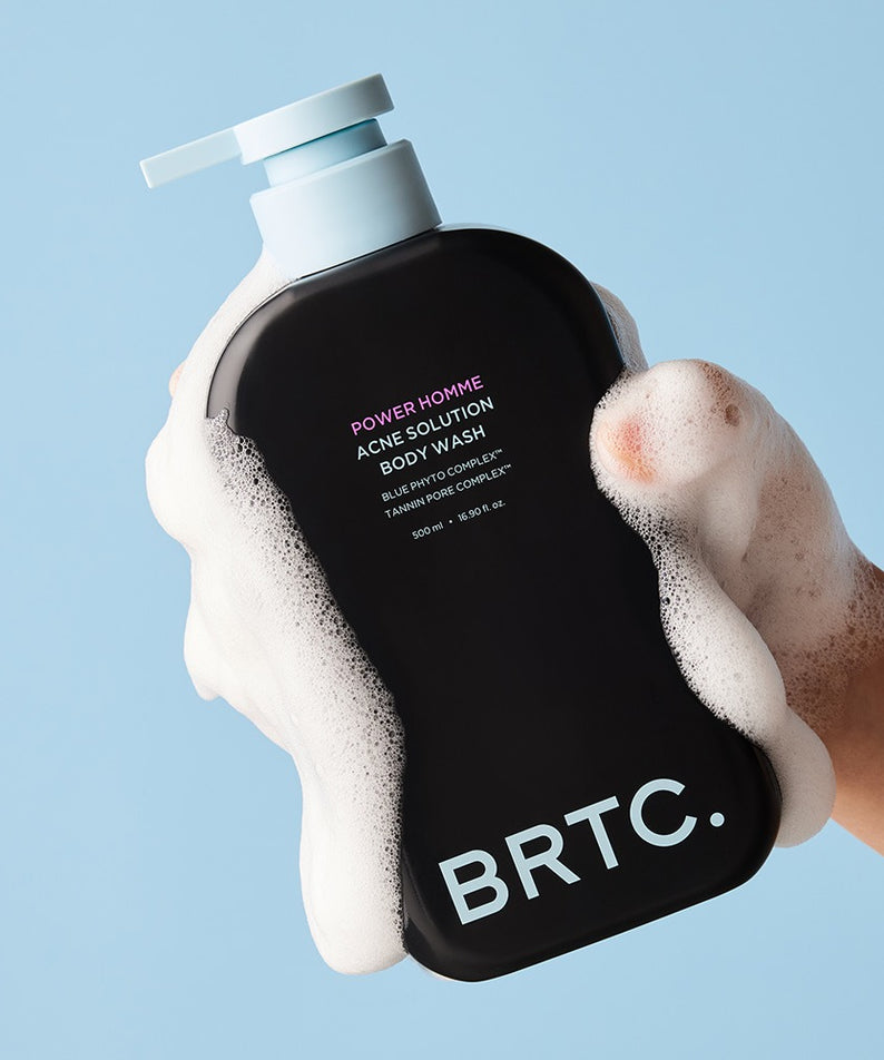 BRTC Power Homme Acne Solution Body Wash 500ml, gel douche BRTC en main avec mousse sur fond bleu