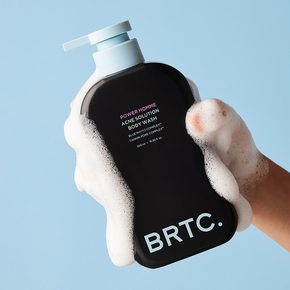 BRTC Power Homme Acne Solution Body Wash 500ml, gel douche BRTC en main avec mousse sur fond bleu