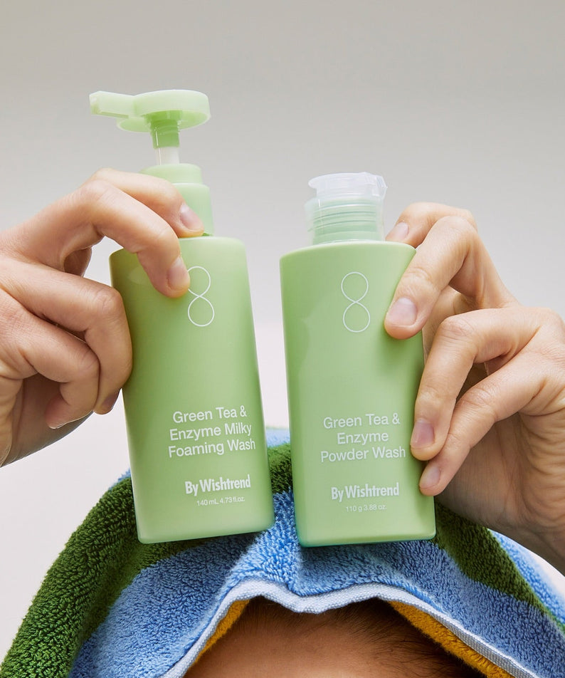 BY WISHTREND Green Tea & Enzyme Powder Wash 110g, mains tenant le produit sur serviette, contexte soin visage.