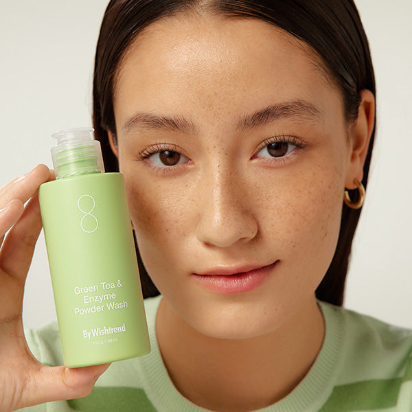 BY WISHTREND Green Tea & Enzyme Powder Wash 110g : bouteille verte tenue par une femme, contexte beauté, photo produit