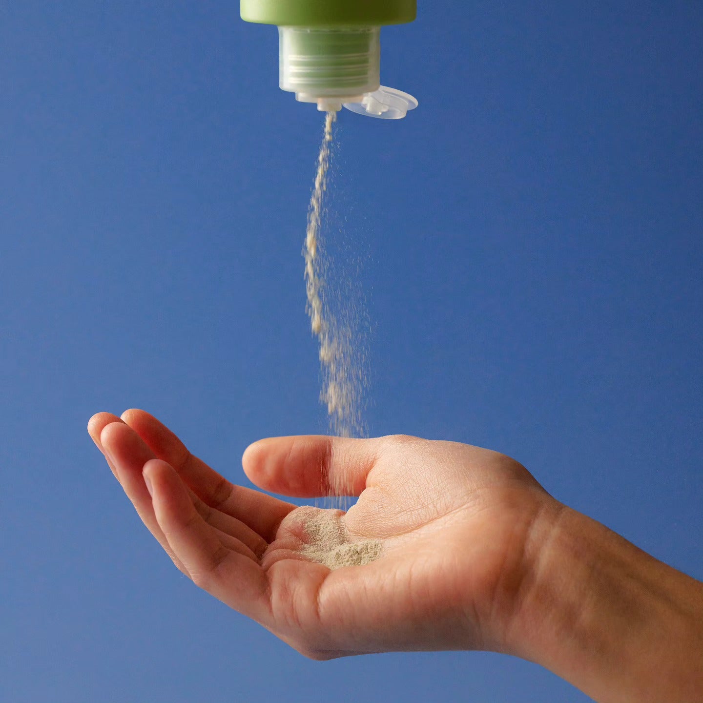 BY WISHTREND Green Tea & Enzyme Powder Wash 110g, marque en bouteille, main sous un jet d’eau sur fond bleu