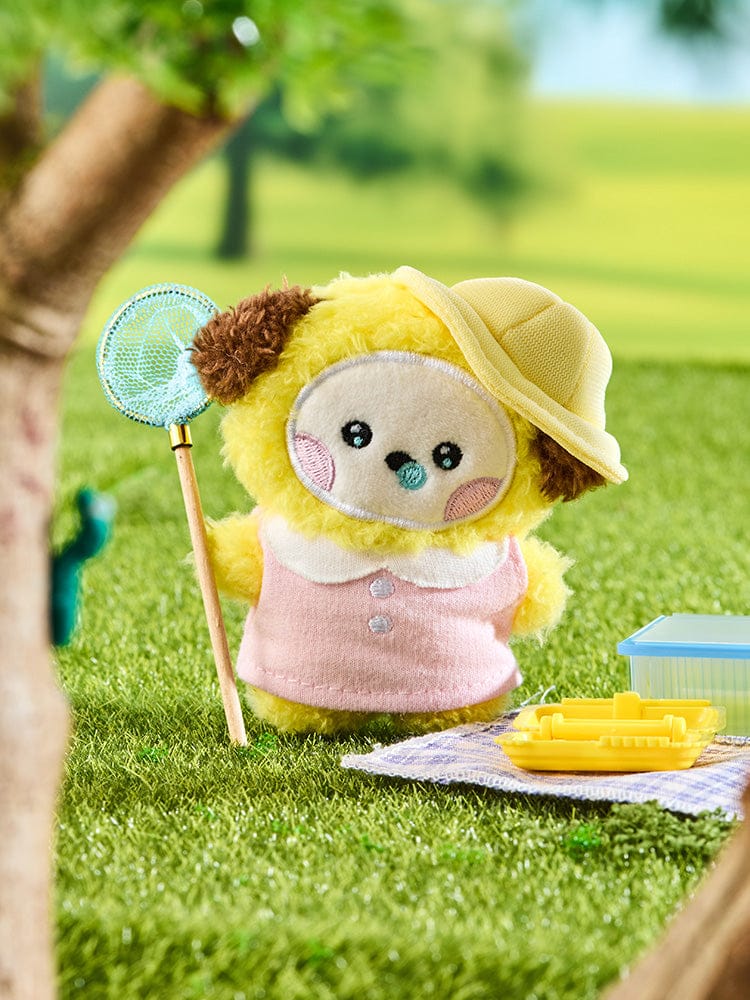 BT21 CHIMMY mini minini PLUSH PICNIC MATE : peluche CHIMMY sur une nappe pique-nique, parc verdoyant en arrière-plan.