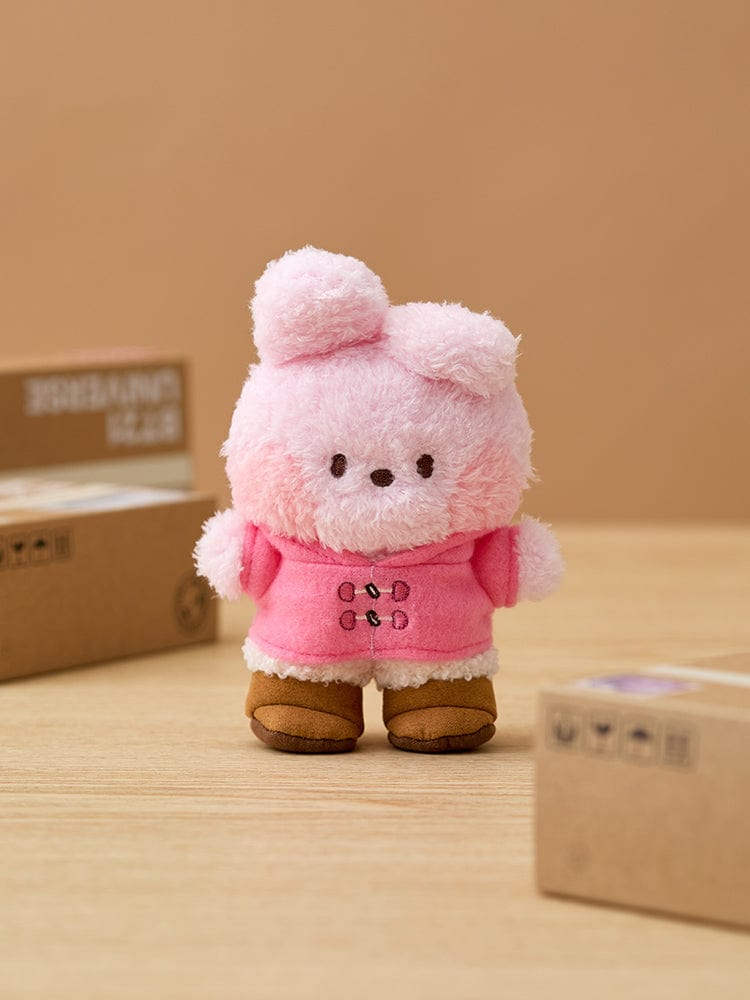 BT21 COOKY minini DOLL BOOTS EDITION, mini peluche COOKY BTS dans un décor sur table avec cartons, style cadeau