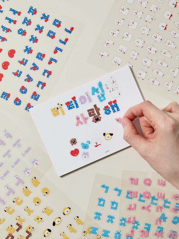 BT21 HANGEUL STICKER SOUVENIR officiel LINE FRIENDS : stickers Hangeul et personnages BTS sur papier, main qui décolle
