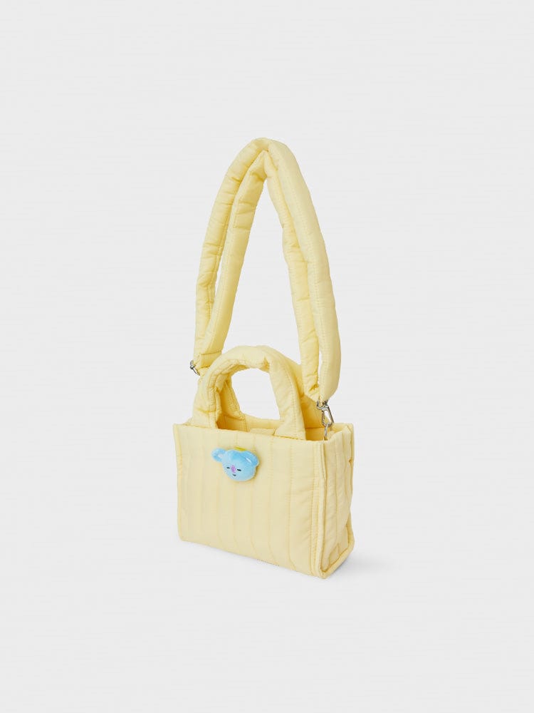 BT21 KOYA QUILTED BAG WITH FACE PLUSH BADGE WINTER EDITION, sac matelassé jaune KOYA avec badge peluche, fond blanc.