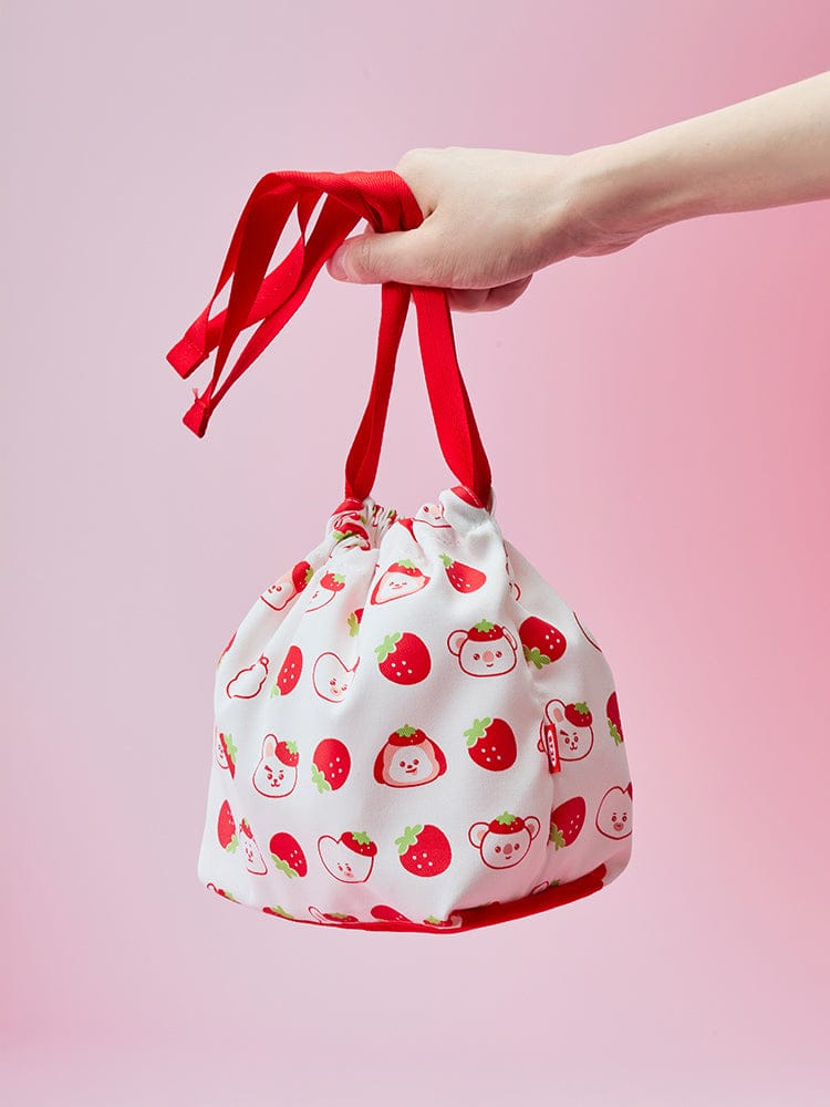 BT21 STRING POUCH STRAWBERRY PARTY : pochette officielle LINE FRIENDS à motifs fraises, main tenant le sac, rose pastel.