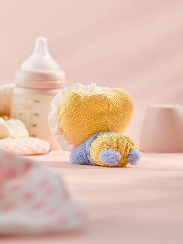 BT21 TATA BABY PLUSH NEWBORN SEASON 2, peluche officielle V BTS, posée avec biberon bébé sur fond rose doux.