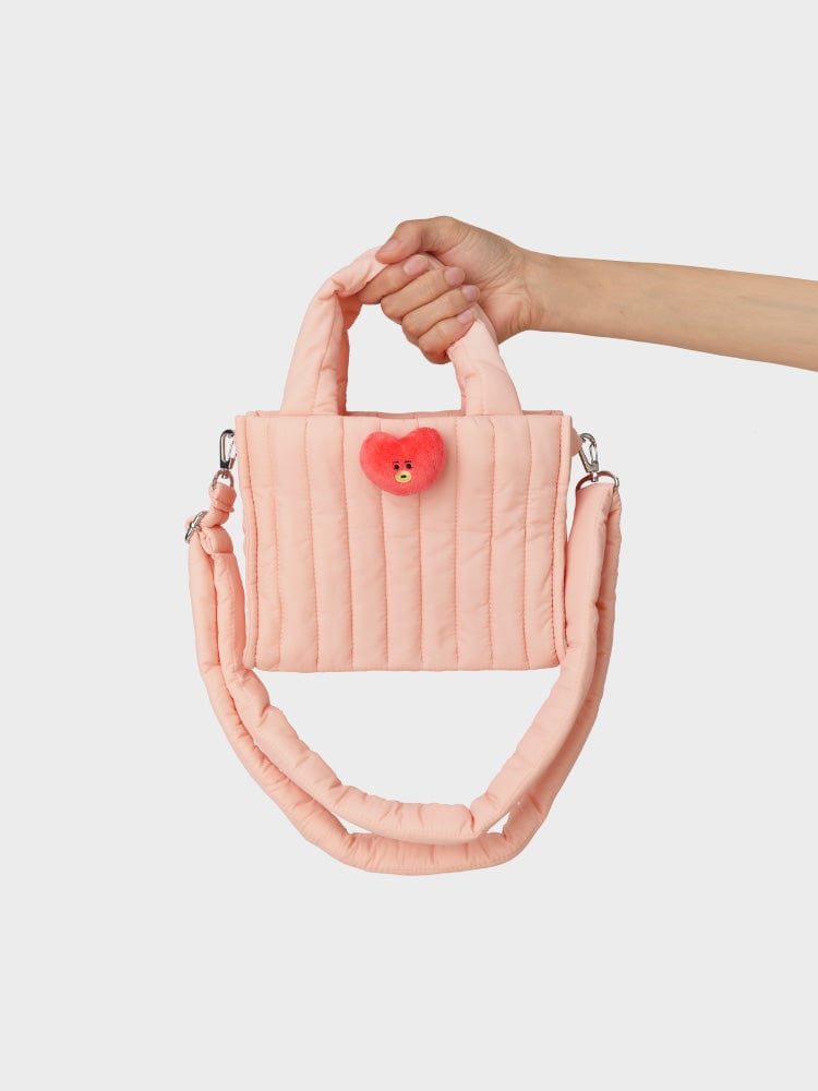 BT21 TATA QUILTED BAG WITH FACE PLUSH BADGE WINTER EDITION : sac matelassé rose TATA avec badge peluche, porté en main.