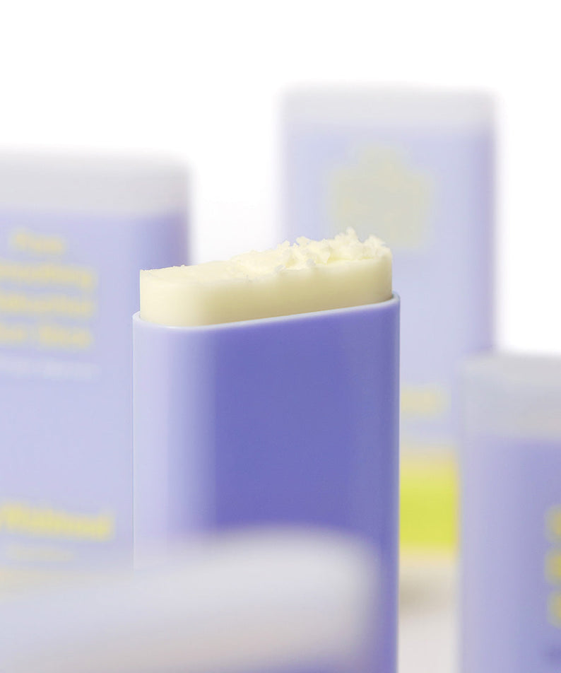 BY WISHTREND Pore Smoothing Bakuchoil Sun Stick 18g, stick solaire violet et crème sur fond cosmétique flou.