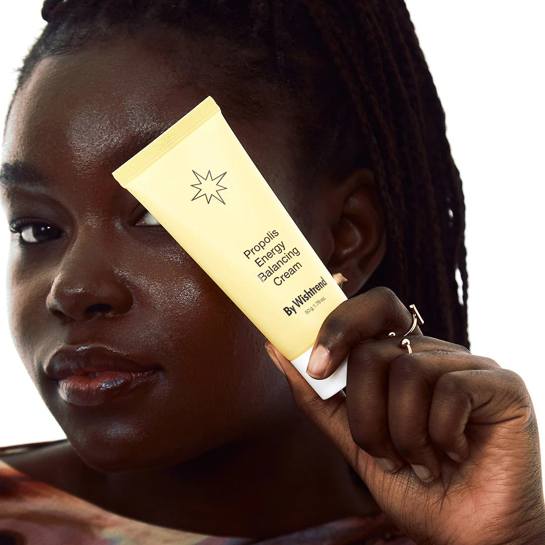 BY WISHTREND Propolis Energy Balancing Cream 50g, tube tenu près du visage sur fond clair, produit de la marque BY WISHTREND