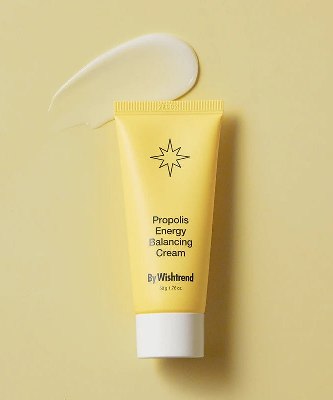 BY WISHTREND Propolis Energy Balancing Cream 50g, tube jaune sur fond beige avec texture de crème, studio beauté