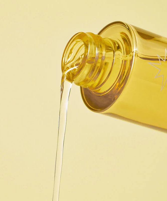 BY WISHTREND Propolis Energy Boosting Essence 100ml en cours de versement d'une bouteille jaune sur fond beige.