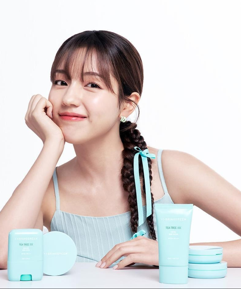 Femme posant avec des produits BRINGGREEN Tea Tree Cica Tone Up Sun Cushion.