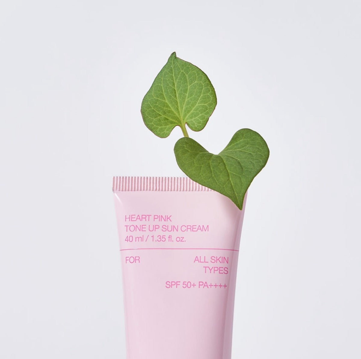 CELIMAX Heart Pink Tone-up Sun Cream 40ml, crème solaire rose sur fond clair avec feuilles, visuel produit de marque.