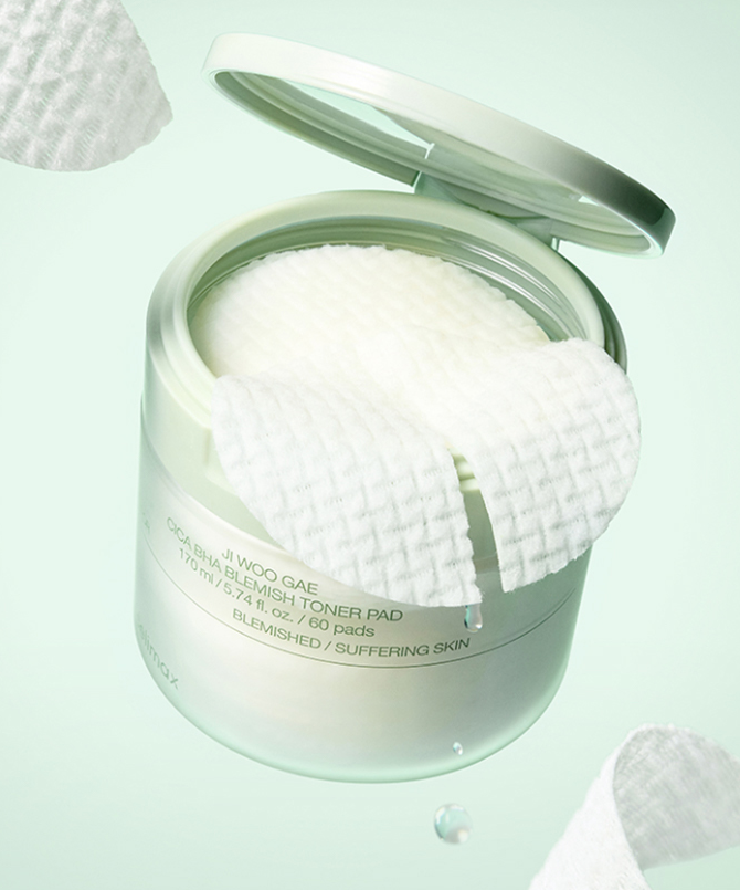 Décris l'image en français : CELIMAX Ji Woo Gae Cica BHA Blemish Toner Pad 60 pads, boîte ouverte avec pads, fond pastel.