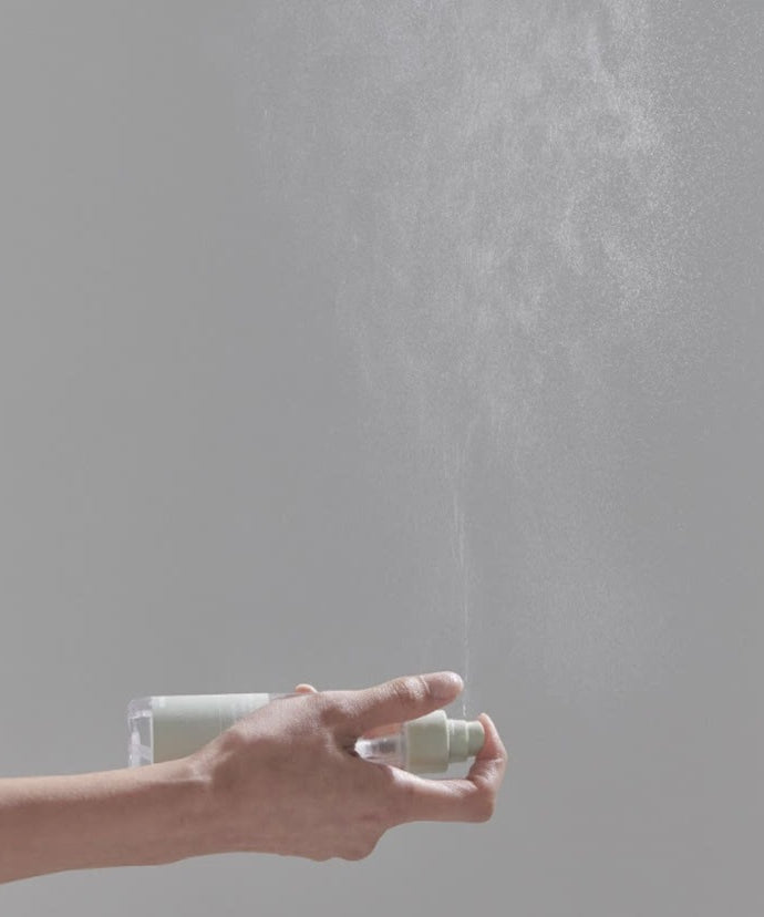 CELIMAX Ji Woo Gae Heartleaf BHA Body Mist 150ml : main en spray, flacon en arrière-plan sur fond gris clair.