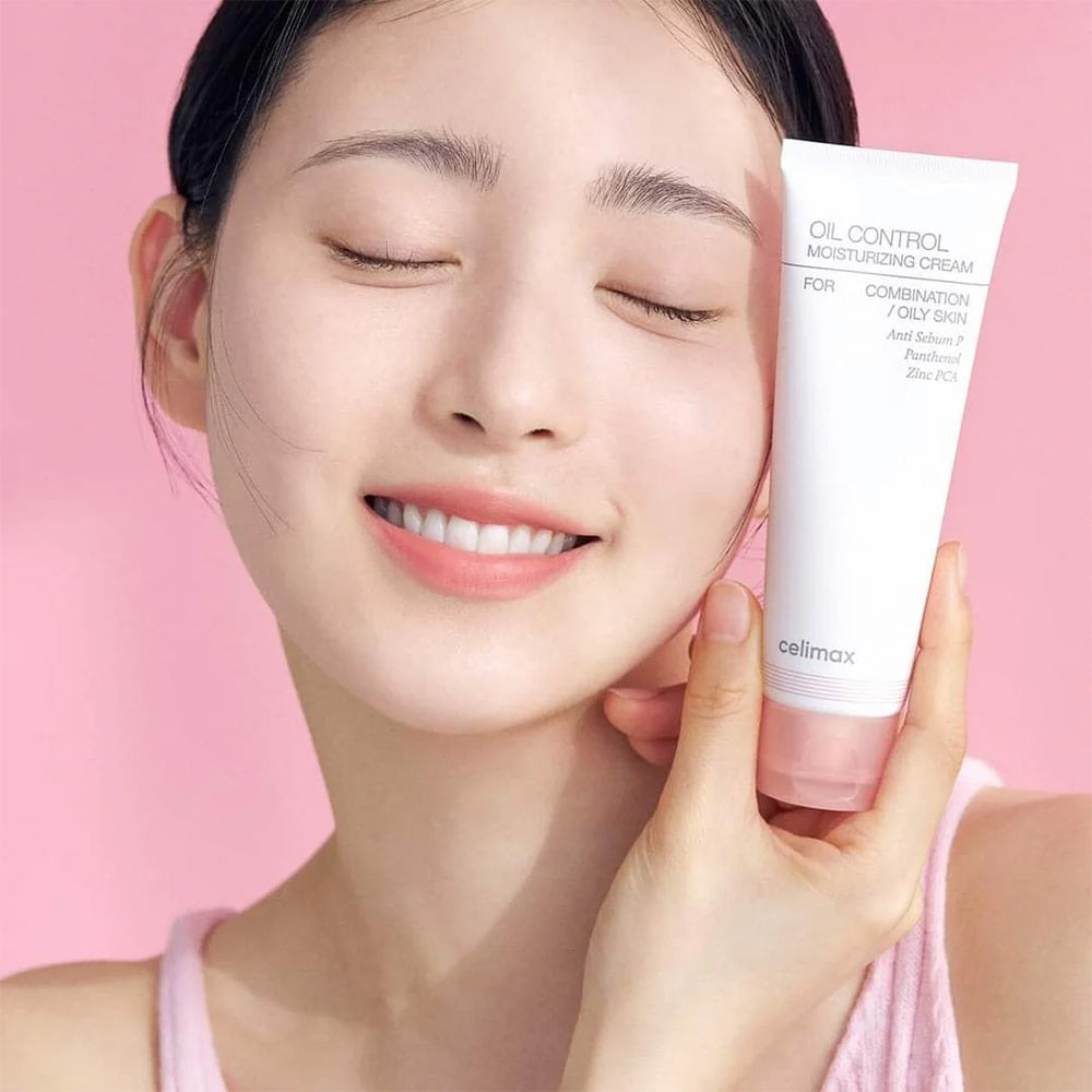 CELIMAX Oil Control Moisturizing Cream 80ml, femme souriante tenant le tube de crème sur fond rose pastel.