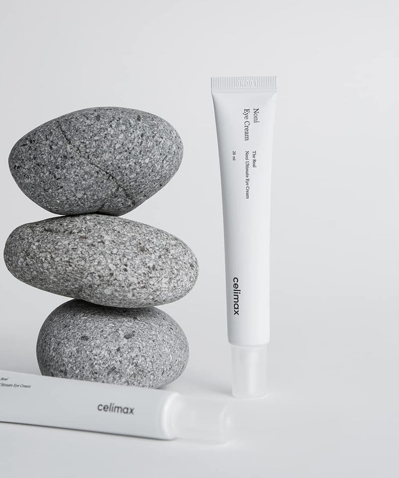 CELIMAX The Real Noni Ultimate Eye Cream 20ml, tube blanc sur pierres grises, fond blanc, produit de marque Celimax