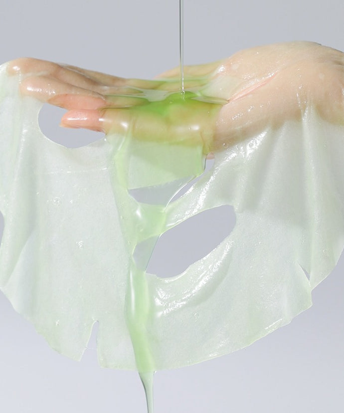 Main tenant un masque CELIMAX Noni Ampoule Mask 10 Sheets, illustrant l'hydratation luxueuse et l'essence verte.