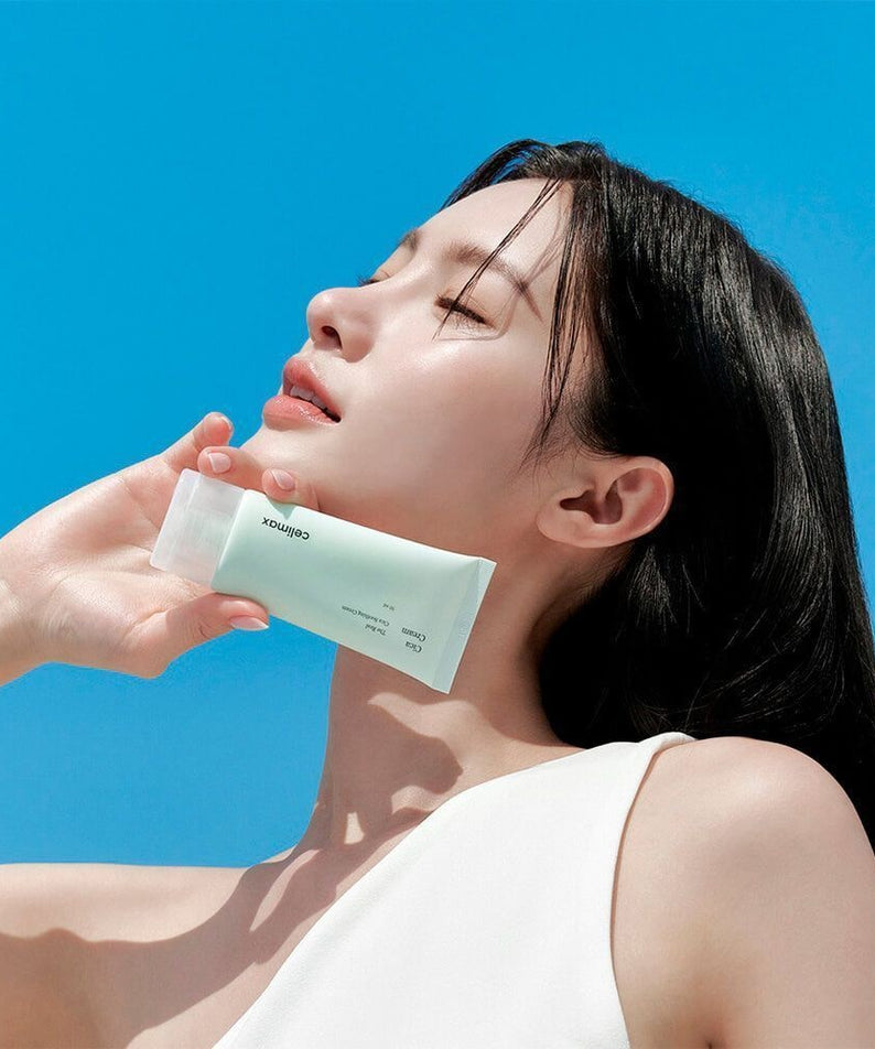 Femme tenant CELIMAX The Real Cica Soothing Cream 50ml sous un ciel bleu, idéal pour apaiser et hydrater la peau.