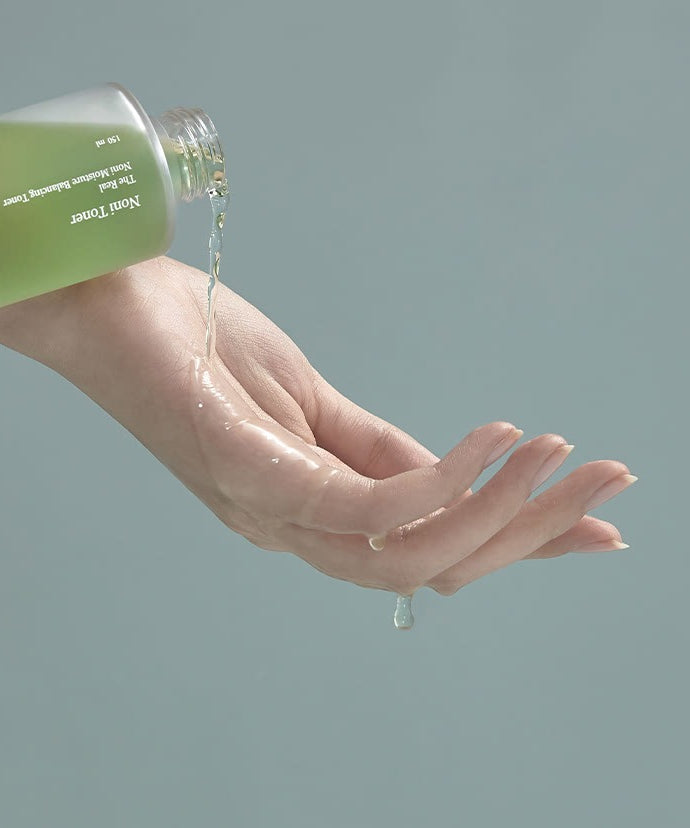 CELIMAX The Real Noni Moisture Balancing Toner 150ml versant liquide sur une main, hydratation et soin de la peau.