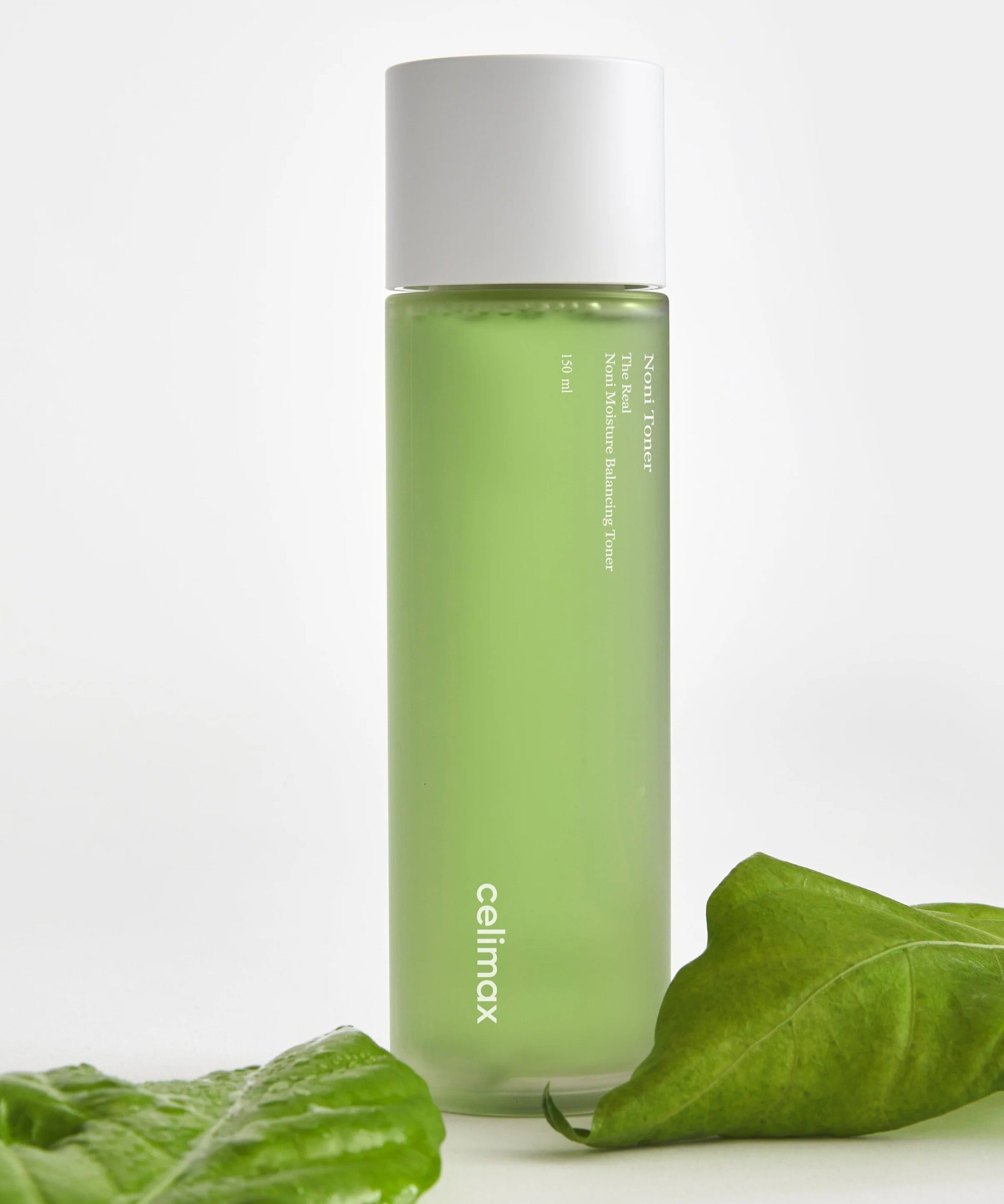 CELIMAX The Real Noni Moisture Balancing Toner 320ml en bouteille vert vif avec des feuilles en arrière-plan, soin de la peau hydratant.
