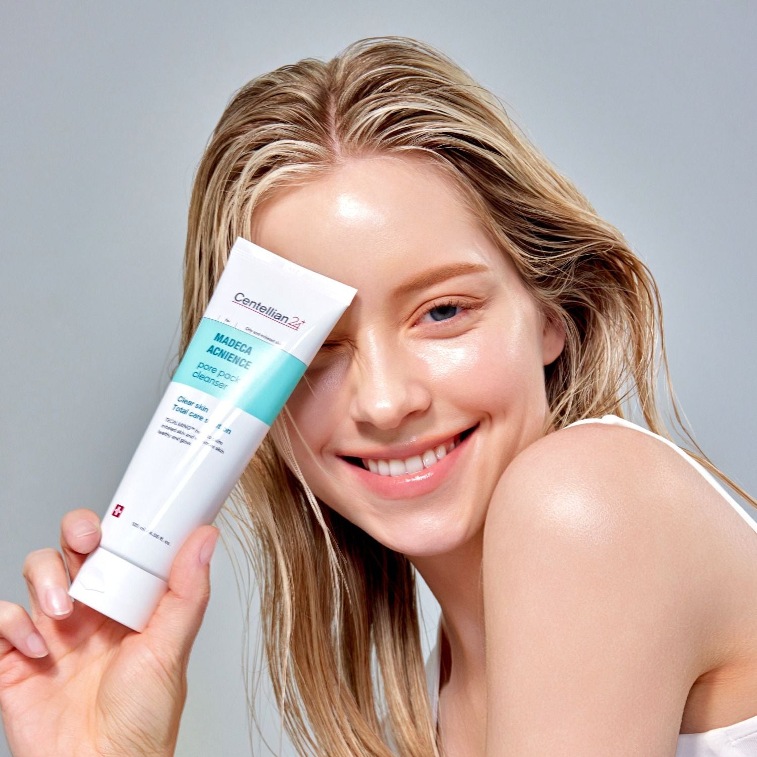 CENTELLIAN 24 Madeca Acnience Pore Pack Cleanser 120ml de la marque, femme souriante tenant le flacon sur fond clair.