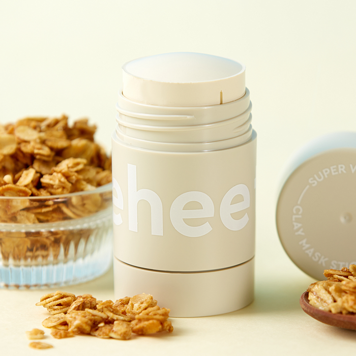 Décris l'image en français : CHARMZONE  Teeheehee Soothing Oat Clay Mask Stick 35g, stick à l’avoine, décor fleurs d’avoine.