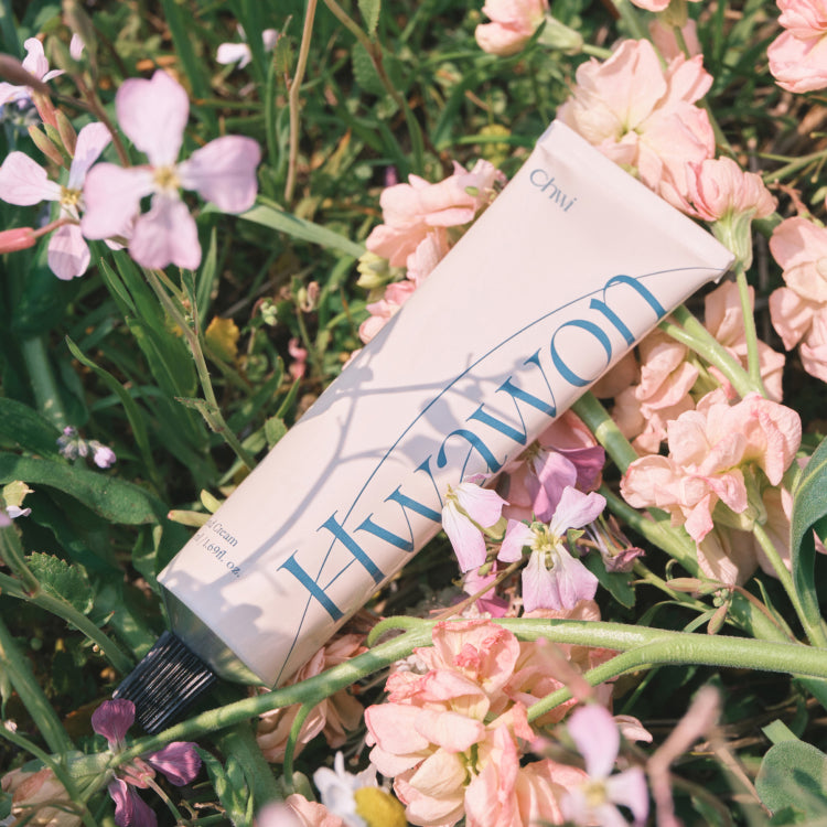 CHWI (CHI) Hwa Won Hand Cream 50ml, tube crème sur fleurs roses et vert, produit CHWI dans un jardin fleuri.