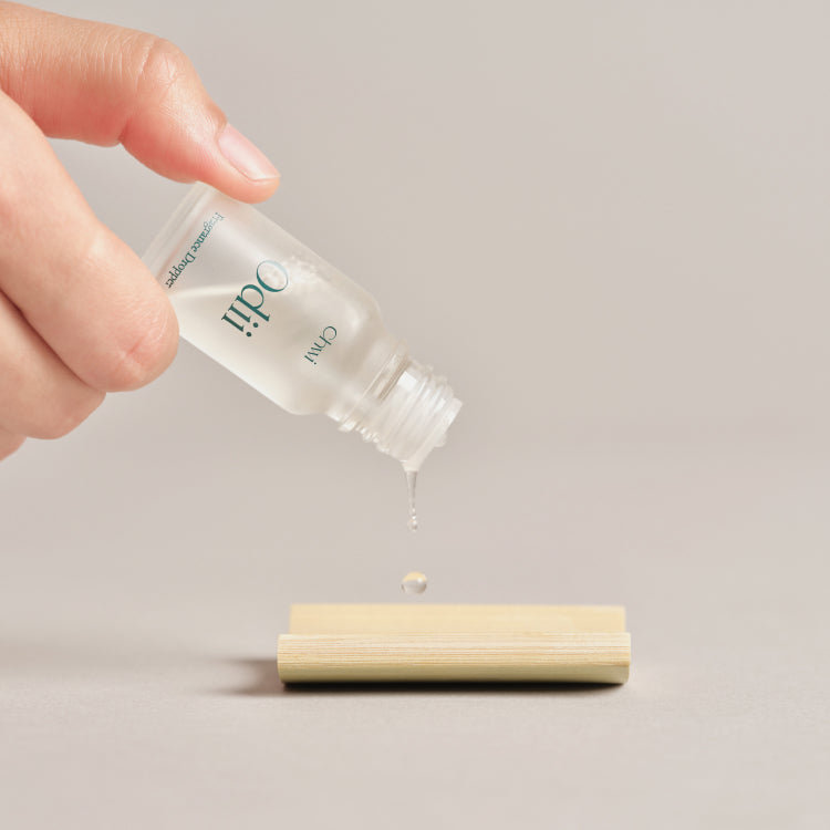 Main tenant CHWI (CHI) Odii Frangrance Dropper 10ml, gouttes vers diffuseur sur fond clair, marque CHWI visible