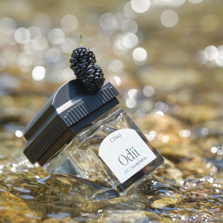 CHWI (CHI) Odii Parfume 50ml, bouteille près d’un blackberry, décor nature flou, marque CHWI (CHI).