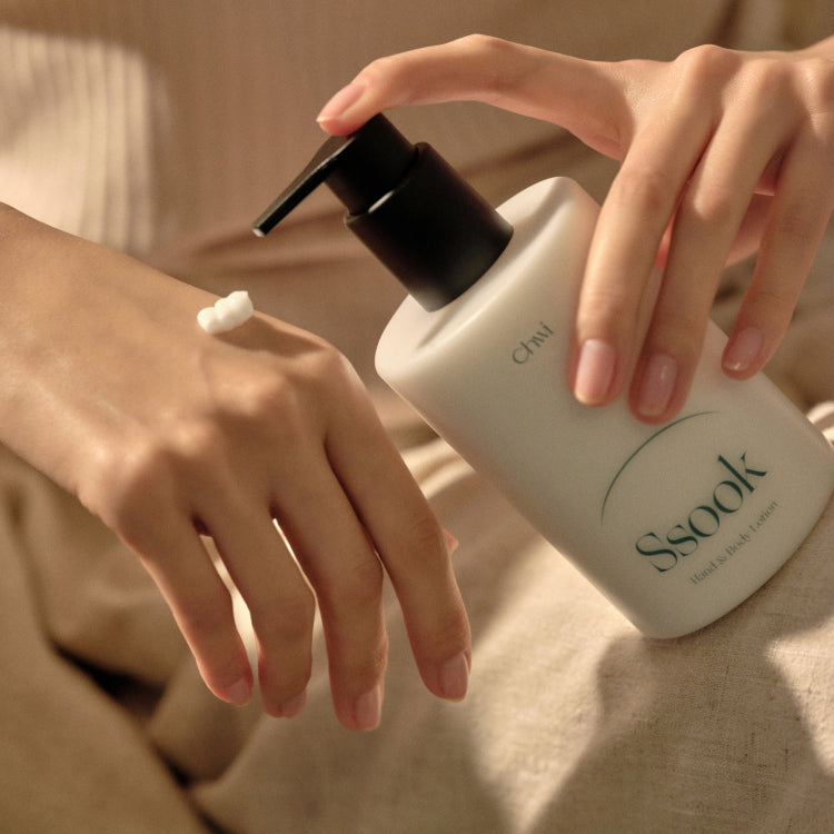CHWI (CHI) Ssook Hand & Body Lotion 300ml : flacon sur peau, crème appliquée, ambiance spa, mains et lumière naturelle.