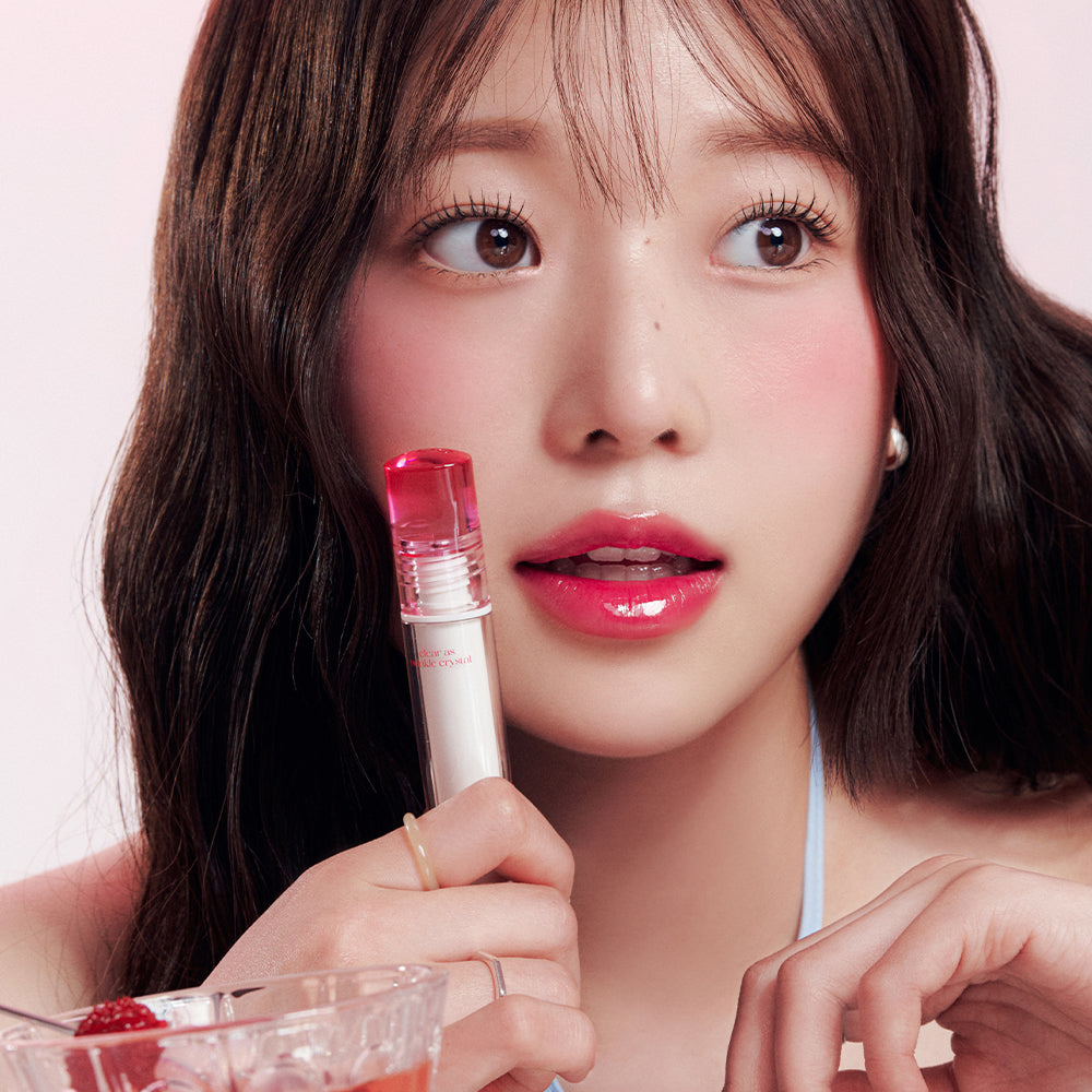 CLIO Crystal Glam Tint de CLIO : femme maquillée tenant un tube, fond clair, look crystal glam.