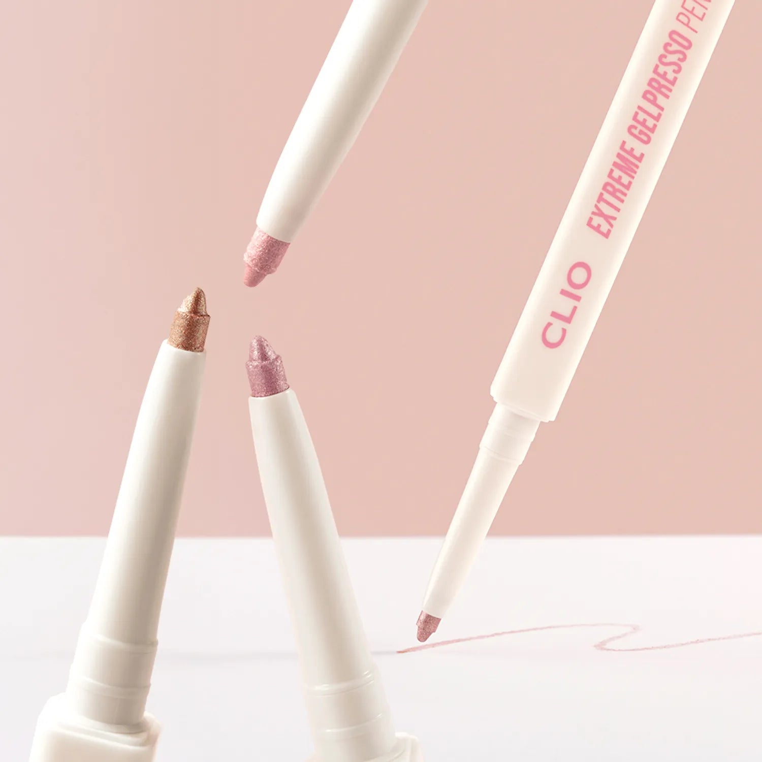 CLIO  NEW Extreme Gelpresso Pencil Liner de CLIO, stylos eyeliner crème sur fond pastel, maquillage en gros plan.