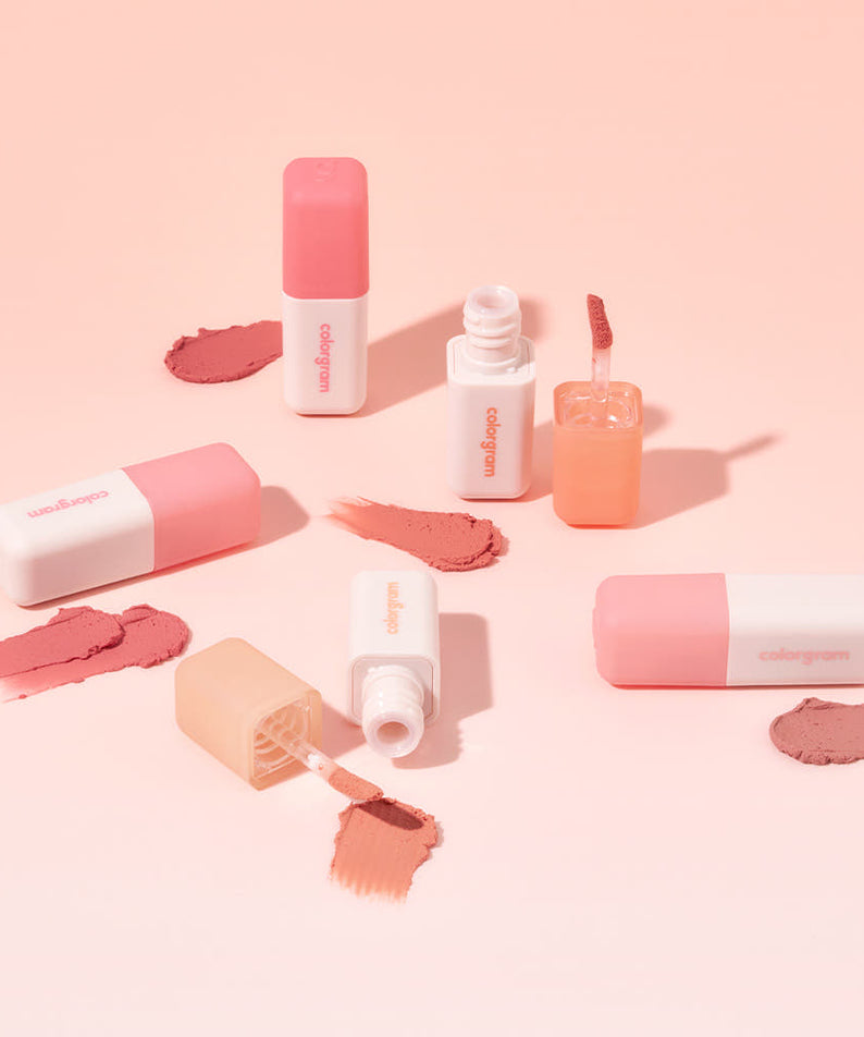 COLORGRAM Nude Blur Tint - Teintes de rouge à lèvres et flacons sur fond beige, ambiance maquillage élégante et moderne.